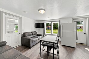 A modern kitchen with a dining table and chairs, a sofa, and a refrigerator. - Andover Retreat • Near Hiking & Boating (Andover)