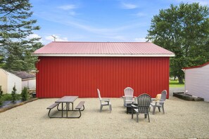 Ein roter Metallschuppen mit einem Picknicktisch und Stühlen davor.