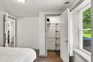 Ein Schlafzimmer mit einem Bett, einem begehbaren Kleiderschrank und einem Fenster mit Blick.