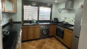 A compact kitchen with a washing machine, oven, and a window with a view. - Mediterranean Getaway (Fnideq)