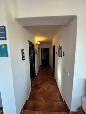 Ein Flur mit Fliesenboden, einer Wandleuchte und einer Tür am Ende.