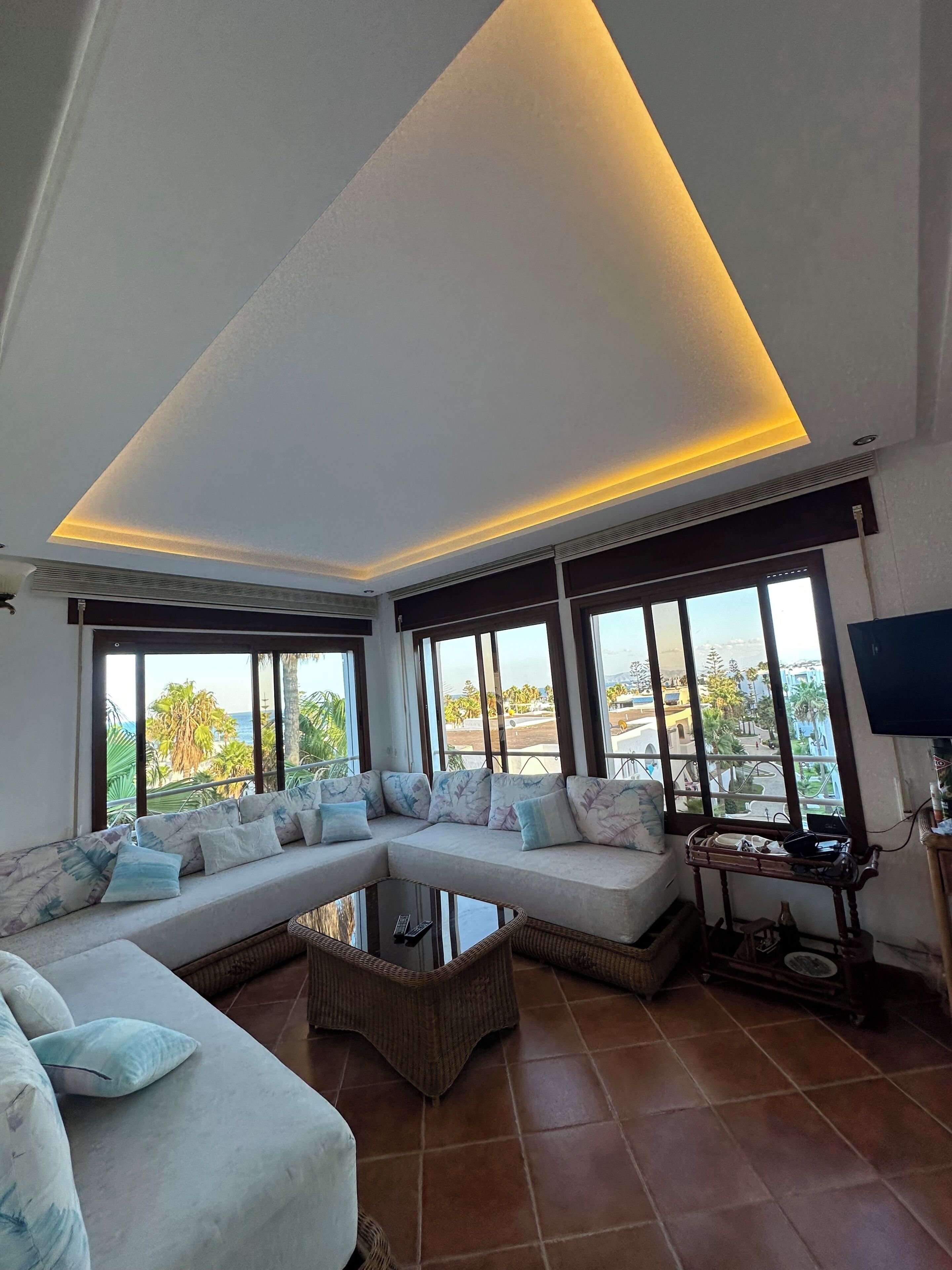 A modern living room with a sectional sofa, a coffee table, and large windows offering a view of the outdoors.