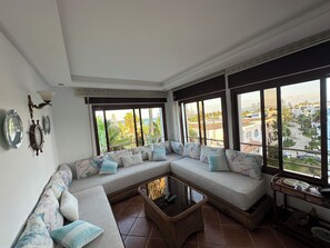 Ein geräumiges Wohnzimmer mit einer großen Eckcouch, einem Couchtisch und Blick auf die Küste.