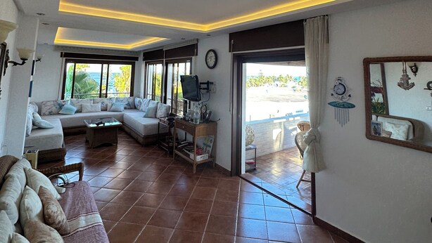 A spacious living area with a sofa set, a television, and a dining table. - Mediterranean Getaway (Fnideq)