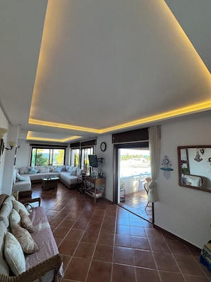 A spacious living area with a sofa set, a television, and a dining table. - Mediterranean Getaway (Fnideq)