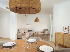 A modern living room with a round dining table set for a meal, a sofa, a chair, and a hanging light fixture. - La Quinta Hills by Interhome (Marbella)
