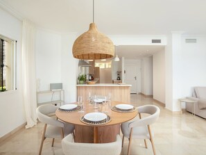 A modern dining area with a round wooden table, four chairs, and a woven pendant light. - La Quinta Hills by Interhome (Marbella)