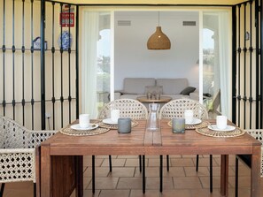 Un coin repas avec une table en bois dressée pour quatre personnes, entourée de chaises en osier.