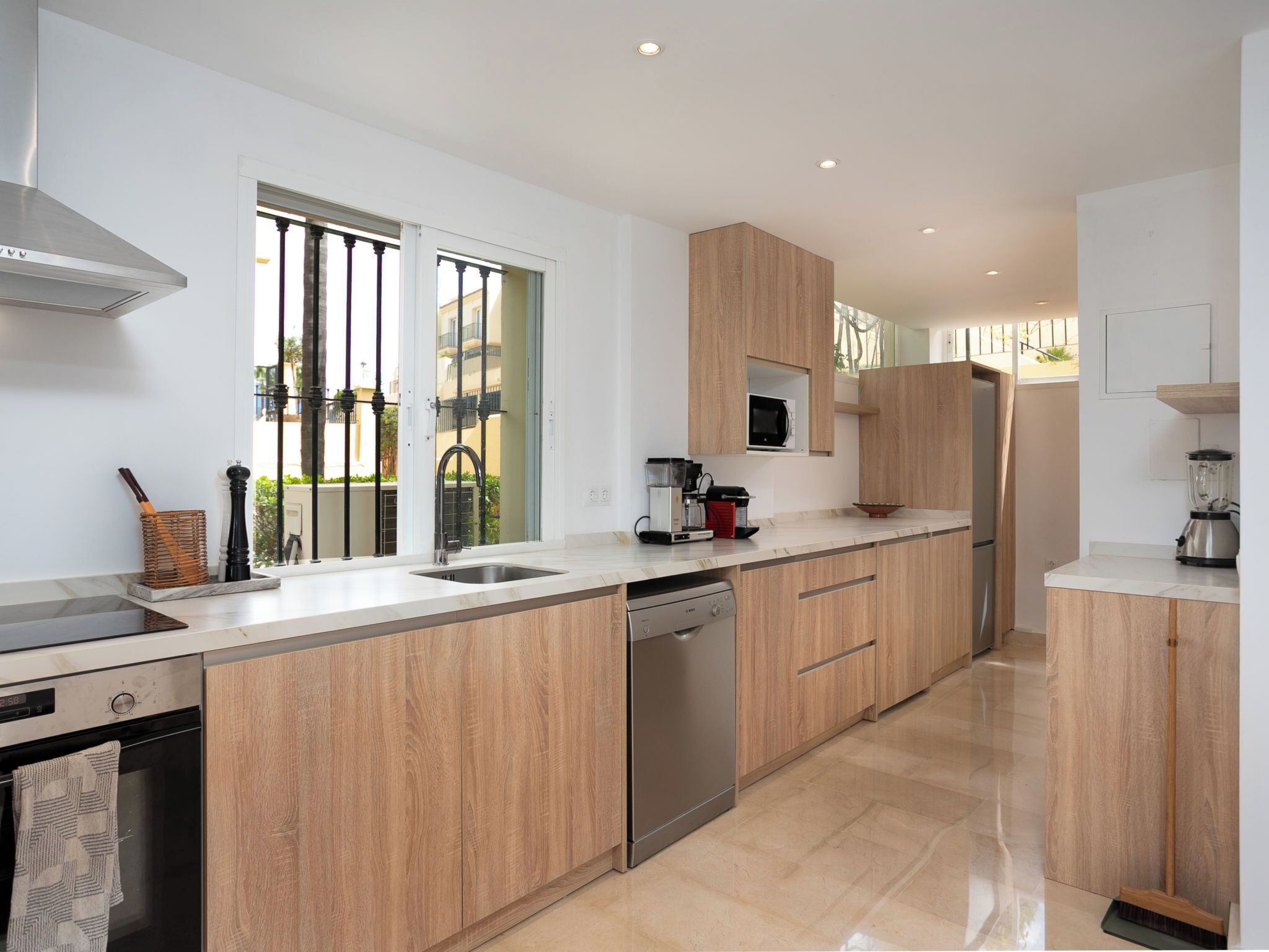 Une cuisine moderne avec des meubles en bois, des appareils électroménagers en acier inoxydable et une grande fenêtre.