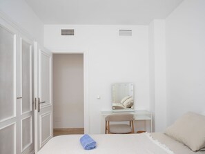 A bedroom with a bed, a vanity with a mirror, and a door with a mesh screen. - La Quinta Hills by Interhome (Marbella)