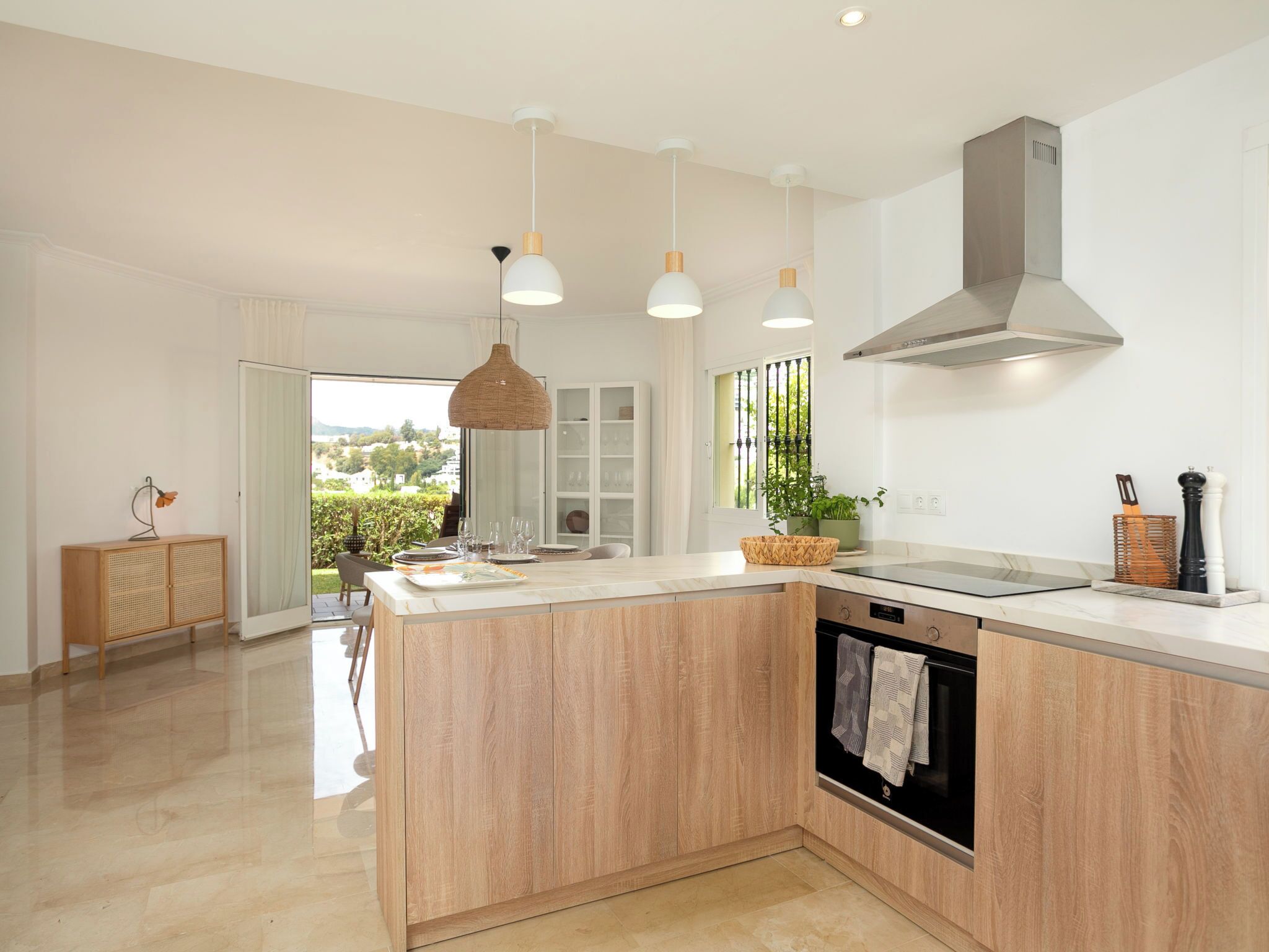 A modern kitchen with a central island, pendant lighting, and a view to the outdoors.