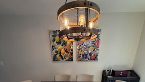 En matplats med ett mörkt träbord, sex stolar och en hängande lampa.