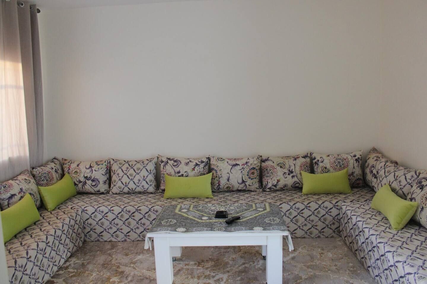 Un coin salon avec des coussins à motifs et une petite table blanche.
