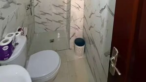 A small bathroom with a toilet, a shower, and a sink.