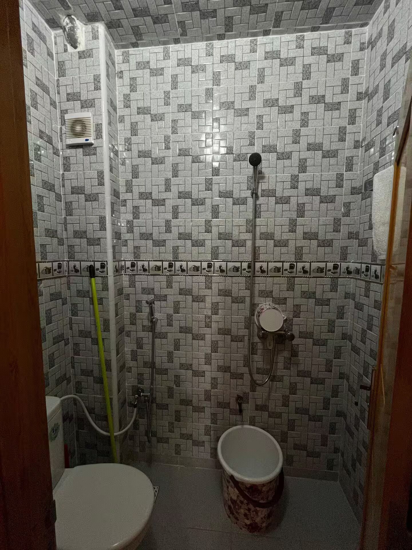 A small bathroom with a toilet, a shower, and a wall-mounted heater.