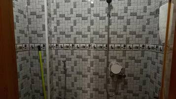 A small bathroom with a toilet, a shower, and a wall-mounted heater.