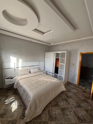 Ein Schlafzimmer mit Bett, Nachttischen, einem Kleiderschrank und einer Badezimmertür.