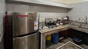Eine Küche mit einem Edelstahlkühlschrank, einem Gasherd und einer gefliesten Spritzschutzwand.