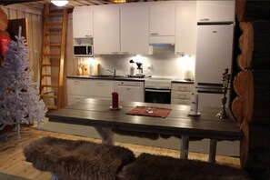Kitchen with a refrigerator and a dining table for shared meals. - Ruka Chalet Roma | Traditional 2BR Log Apt | Sauna (Ruka)