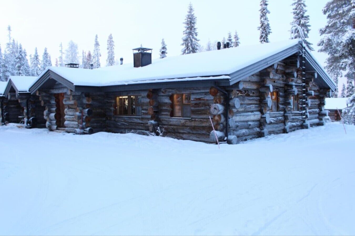The kelo-log chalet surrounded by deep snow on a winter evening.