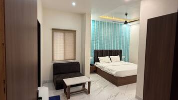 A modern bedroom with a bed, bedside table, and a sofa.