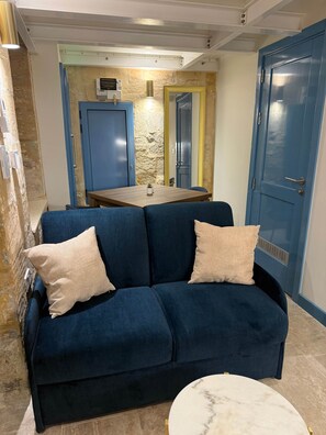 Ein Zimmer mit einem blauen Sofa, einem kleinen Tisch und einem Marmortisch.