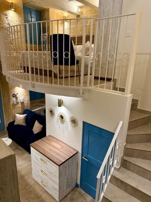 Ein mehrgeschossiges Interieur mit einer Treppe, einer blauen Tür, einer weißen Geländer und einem Sofa.