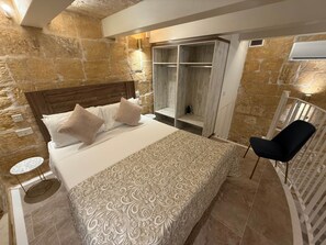 Ein Schlafzimmer mit einem großen Bett, einem Holz-Kopfstück, einem eingebauten Kleiderschrank, einem runden Tisch und einem Stuhl.