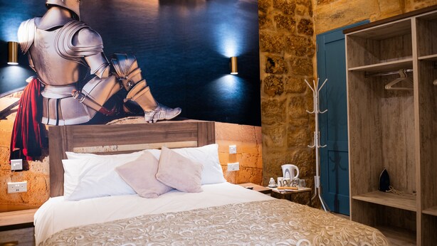 Una camera da letto con un letto grande, un muro in pietra, un armadio in legno e un lampadario a parete.
