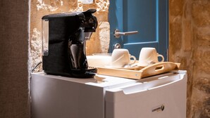 Una macchina da caffè su un bancone con un vassoio di tazze e una porta blu sullo sfondo.