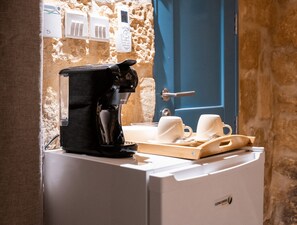 Eine Kaffeemaschine auf einer Theke, mit einem Tablett voller Tassen und einer blauen Tür im Hintergrund.