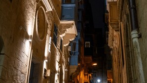 Una stretta via fiancheggiata da edifici, con balconi e un marciapiede bagnato.