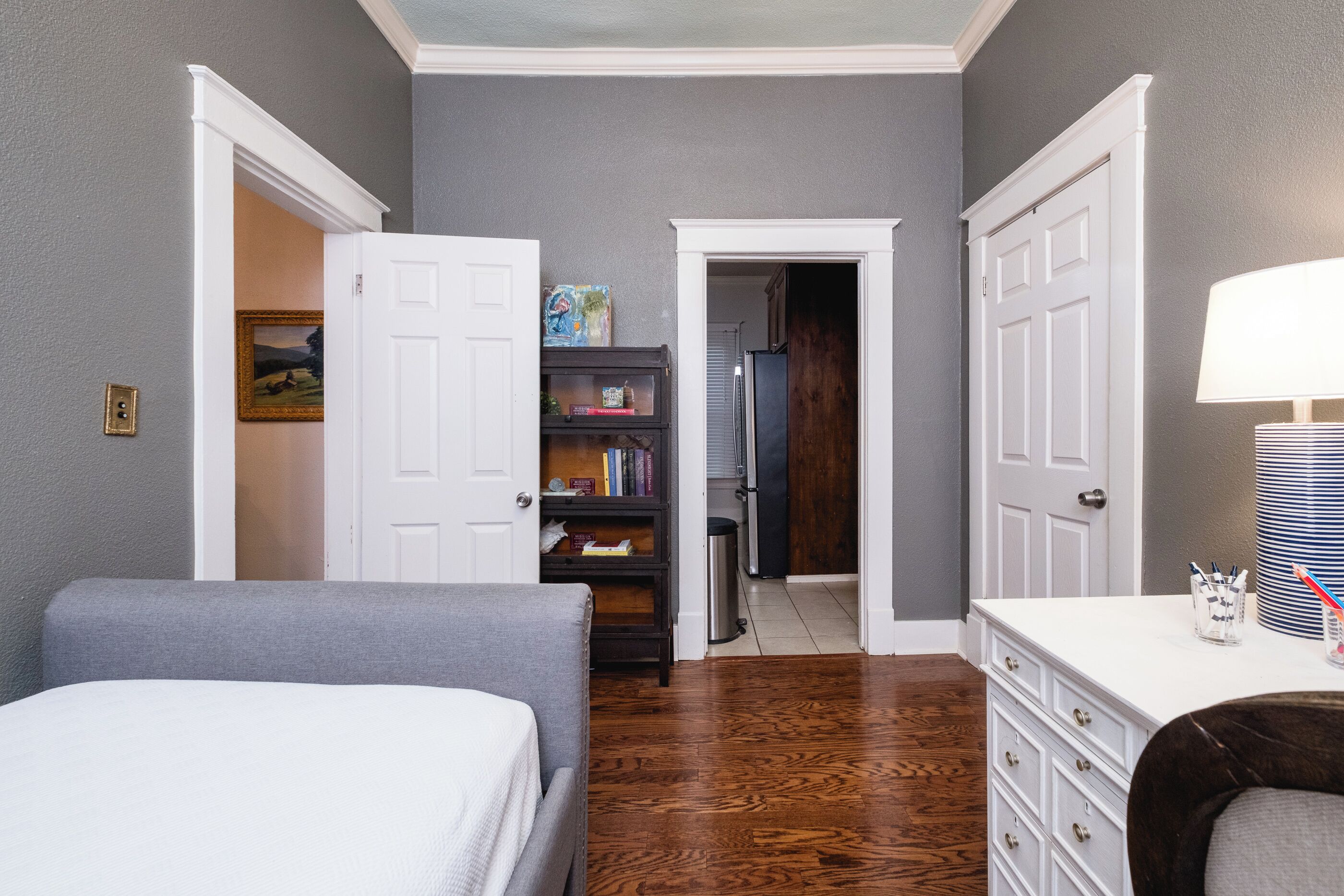 Una habitación con cama, cómoda, escritorio y estantería.