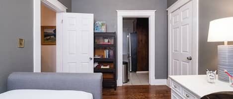 Una habitación con cama, cómoda, escritorio y estantería.