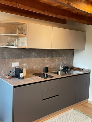 Eine moderne Küche mit Marmorarbeitsplatte, schwarzen Schränken und einem eingebauten Backofen.