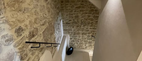 A staircase with stone walls and a handrail.