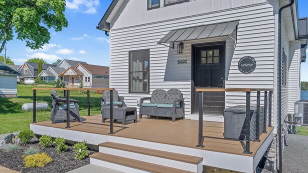A two-story house with a covered porch, a black front door, and a number '14026' on the wall. - Shoreline Retreat - New Modern Luxury Waterfront Escape -Dock & Water Toys (Sterling)