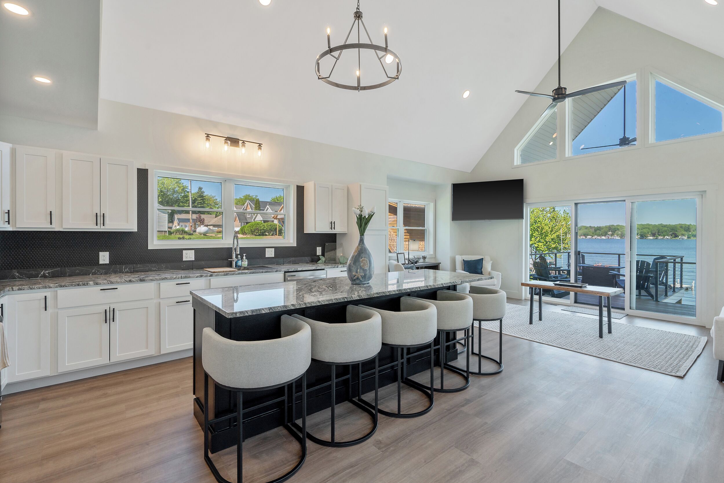 A modern kitchen with a large island, bar stools, and a view of the outdoors.