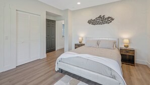 A bedroom with a bed, nightstands, a wall art piece, and a closet. - Shoreline Retreat - New Modern Luxury Waterfront Escape -Dock & Water Toys (Sterling)
