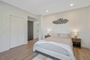 A bedroom with a bed, nightstands, a wall art piece, and a closet. - Shoreline Retreat - New Modern Luxury Waterfront Escape -Dock & Water Toys (Sterling)