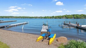 A calm lake with a dock and a kayak. - Shoreline Retreat - New Modern Luxury Waterfront Escape -Dock & Water Toys (Sterling)