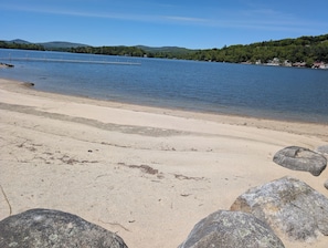 A beach with a clear view of the water and distant hills.