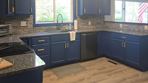A kitchen with dark blue cabinets, a granite countertop, a stainless steel sink, and a black dishwasher. - NewFound LakeHouse! 225' totally PRIVATE Sandy Beach! W-O-W!  (Bristol)