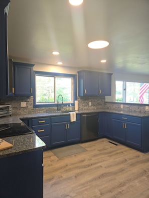 A kitchen with dark blue cabinets, a granite countertop, a stainless steel sink, and a black dishwasher. - NewFound LakeHouse! 225' totally PRIVATE Sandy Beach! W-O-W!  (Bristol)