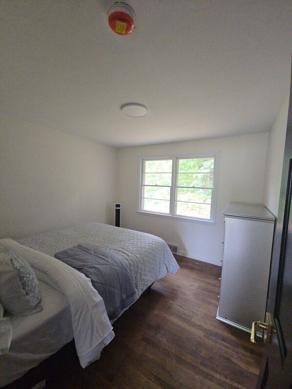 A bedroom with a bed, a window, and a radiator.