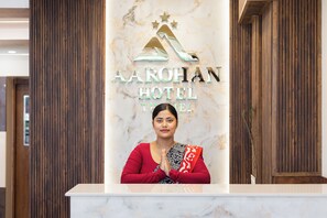 Mostrador de recepción en el HOTEL AROHAN con encimera de mármol y un panel de madera de fondo.