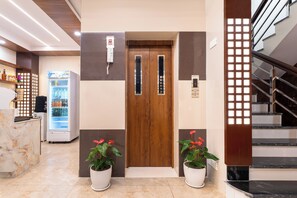 A hotel lobby with a reception desk, a refrigerator, a wooden door, and a staircase. - Aarohan Hotel Thamel (Kathmandu)