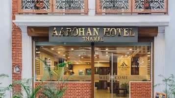 Exterior del HOTEL AAROHAN THAMEL, con una entrada despejada, un balcón con barandillas decorativas y un letrero para el Restaurante en la Azotea.