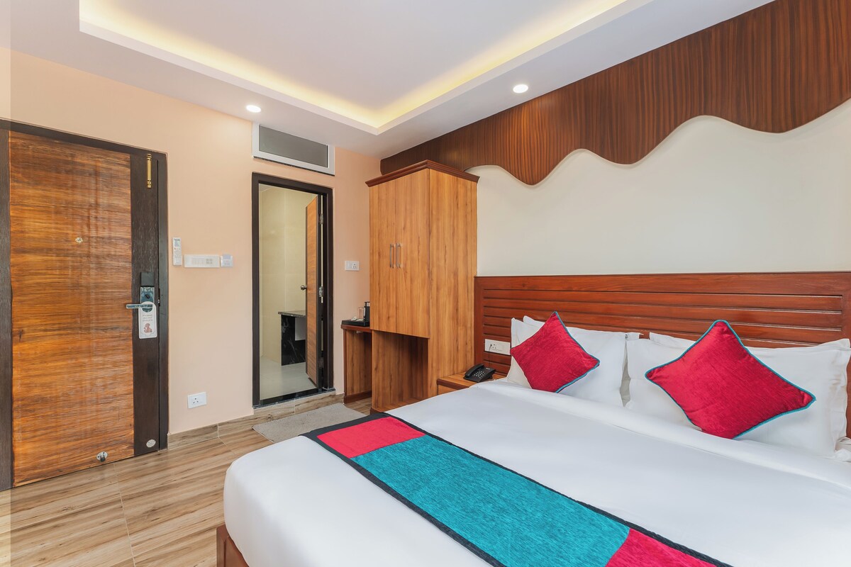 A hotel room with a large bed, wooden wardrobe, and a bathroom visible through an open door.