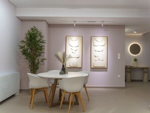 Uma área de refeições moderna com uma mesa redonda, quatro cadeiras, uma planta em vaso e duas luminárias fixadas na parede.